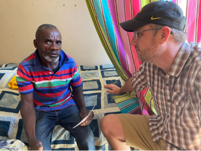 Tim, CEO and Founder of Many Hands, sits in conversation with Bygone in his apartment, illustrating the personal connection and individualized support provided through our community outreach programs in Haiti.