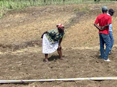 Community members standing in a tilled field preparing for planting, illustrating the sustainable agricultural development projects led by Many Hands to support local livelihoods.