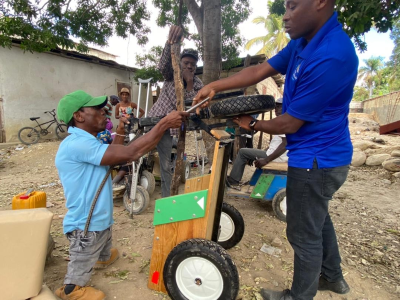 Jean Philippe, Many Hands staff member, fixes a PET cart for a man with no legs, offering him hope and security