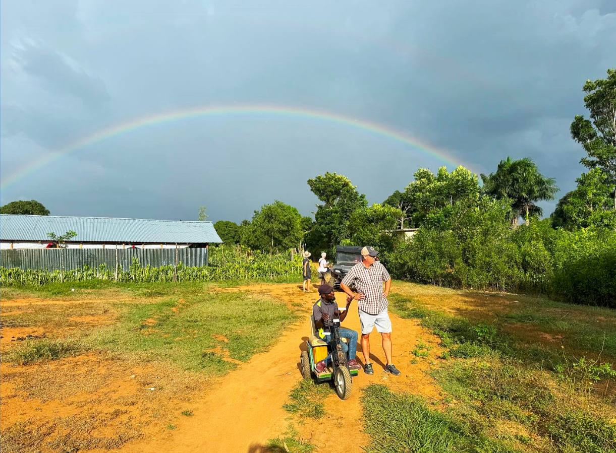 Tim Brand stands with Joslin under a rainbow in Haiti, representing the promises and hope amid struggle.