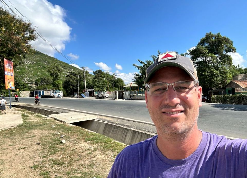 Tim Brand smiling near a road in Haiti