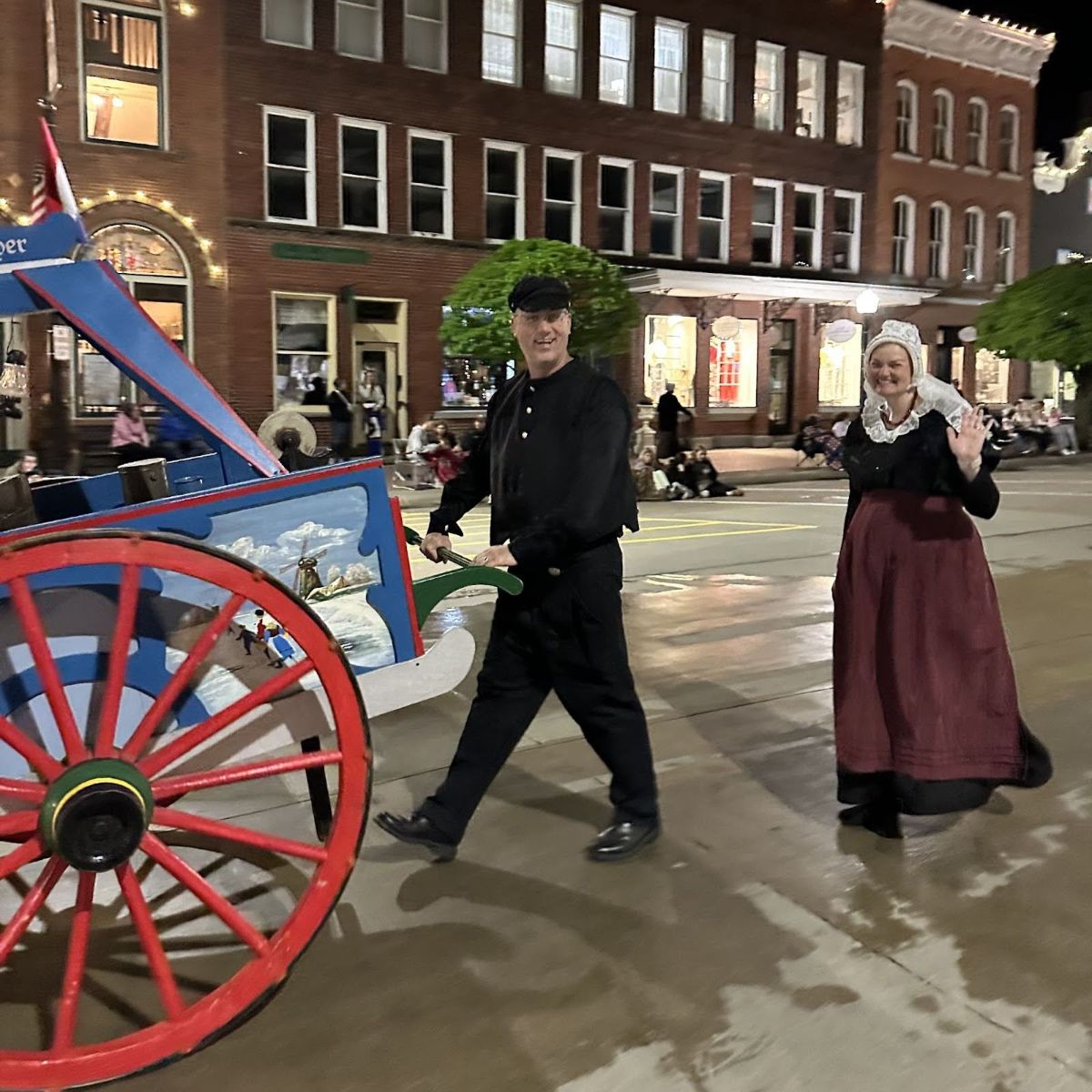 Tim happily pushing a cart in Pella's Tulip Time parade while his wife Catie smiles beside him