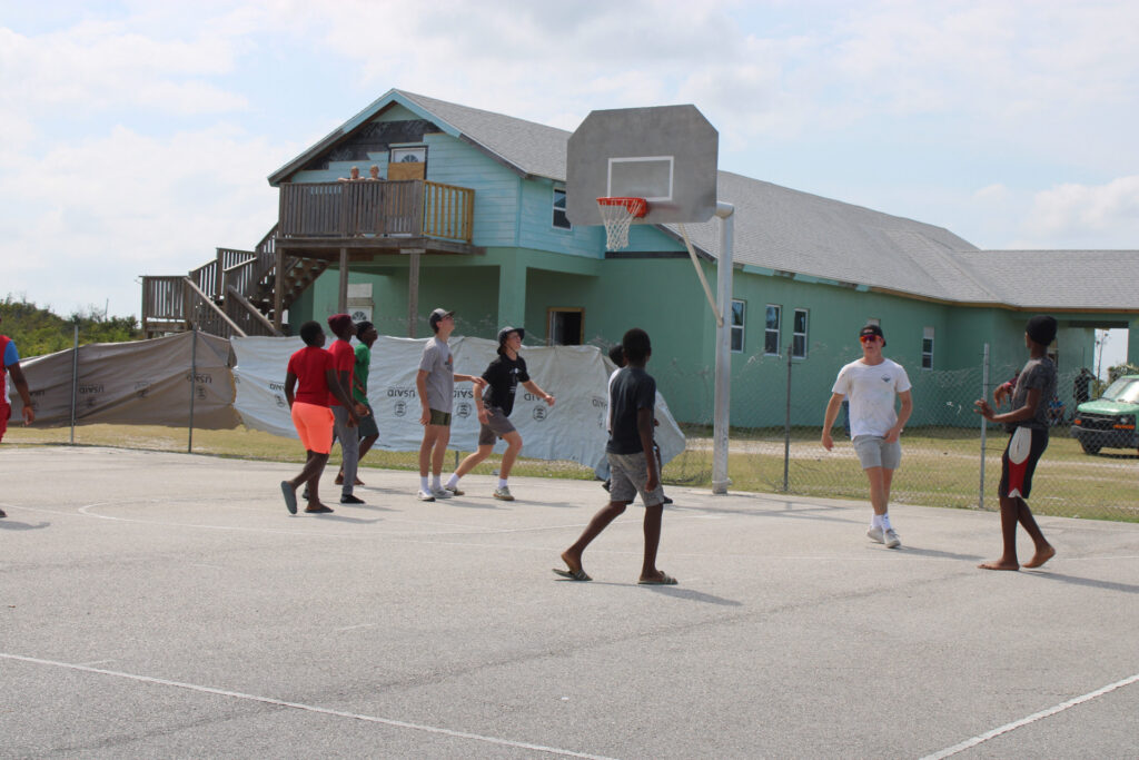 Team members and community members play a quick game of basketball.