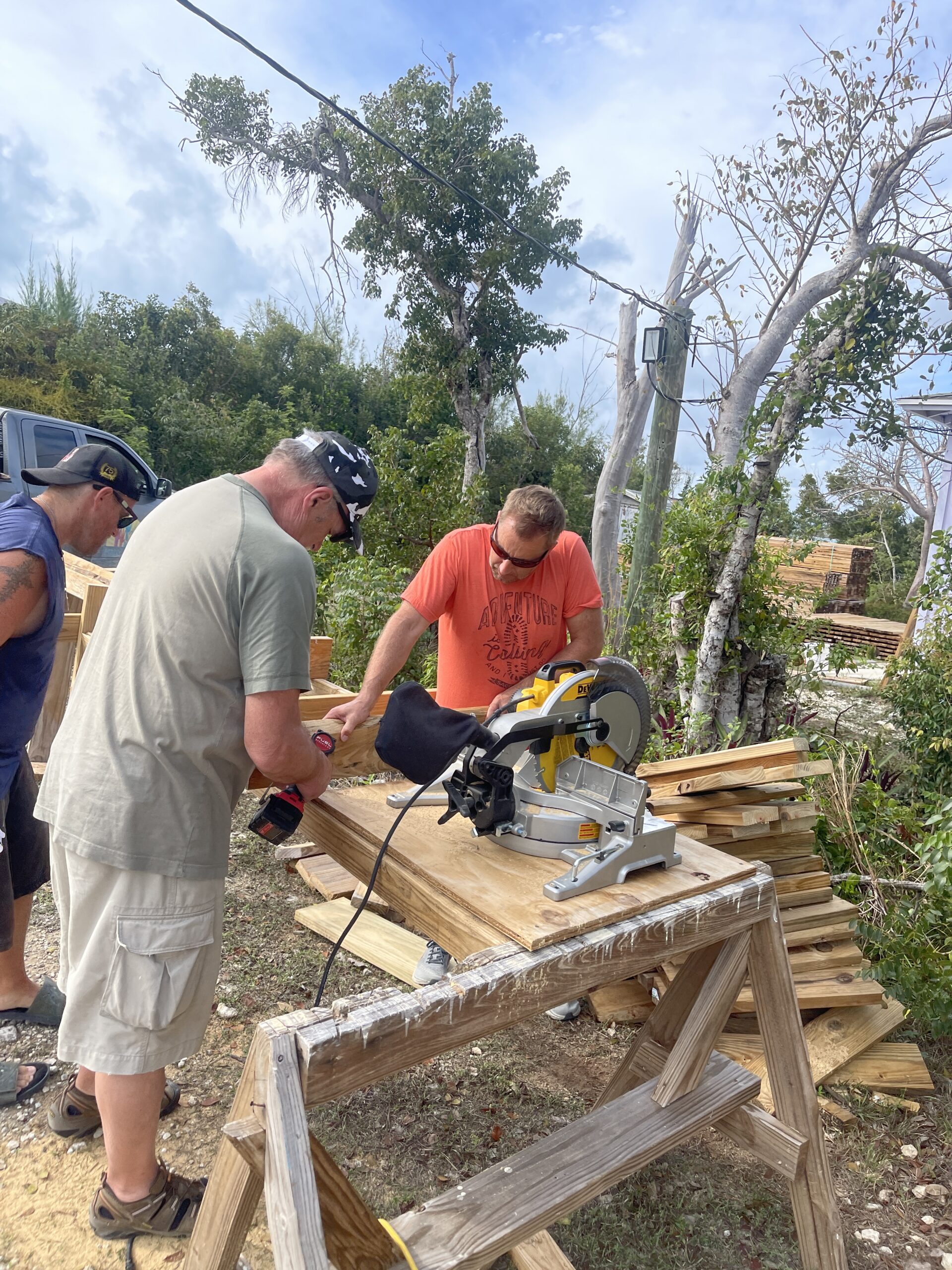 Three men cutting treated wood for bunk beds outside
