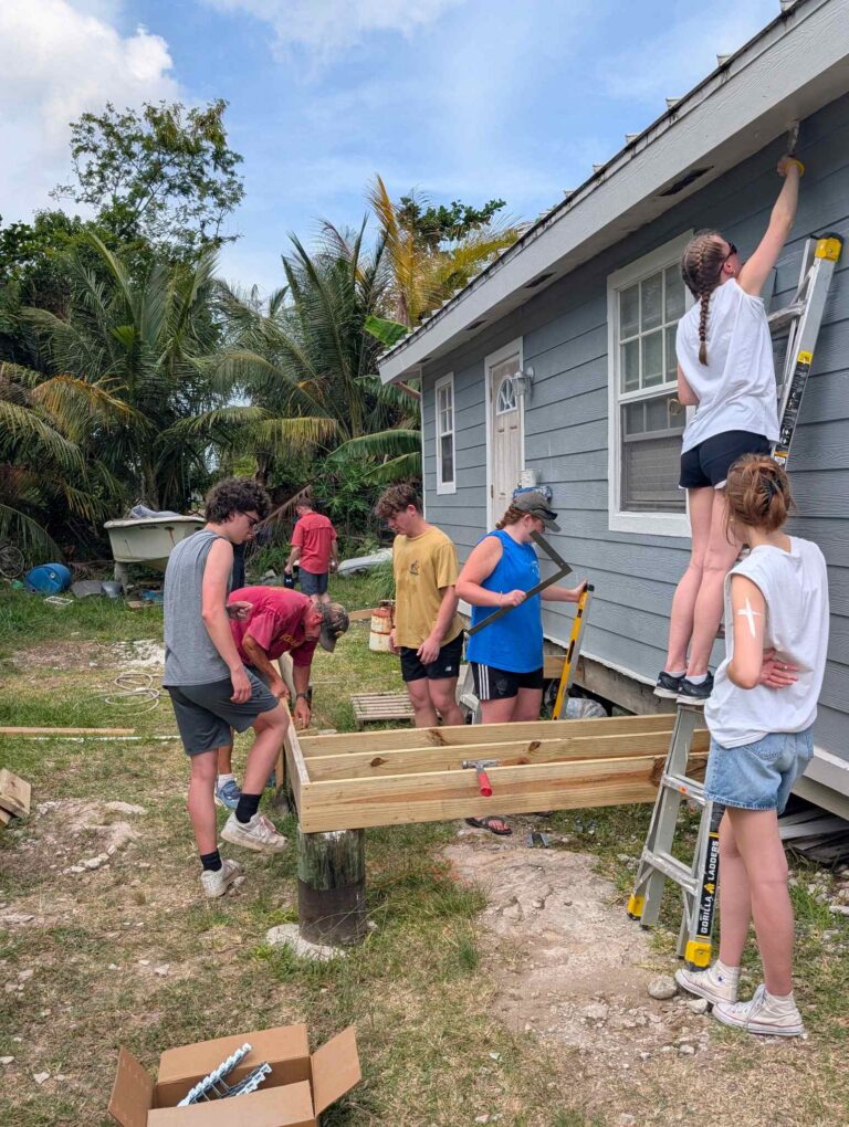 Volunteers and local partners work together to frame out a new timber front porch at Davia's house, advancing hurricane recovery and sustainable infrastructure development with Many Hands.