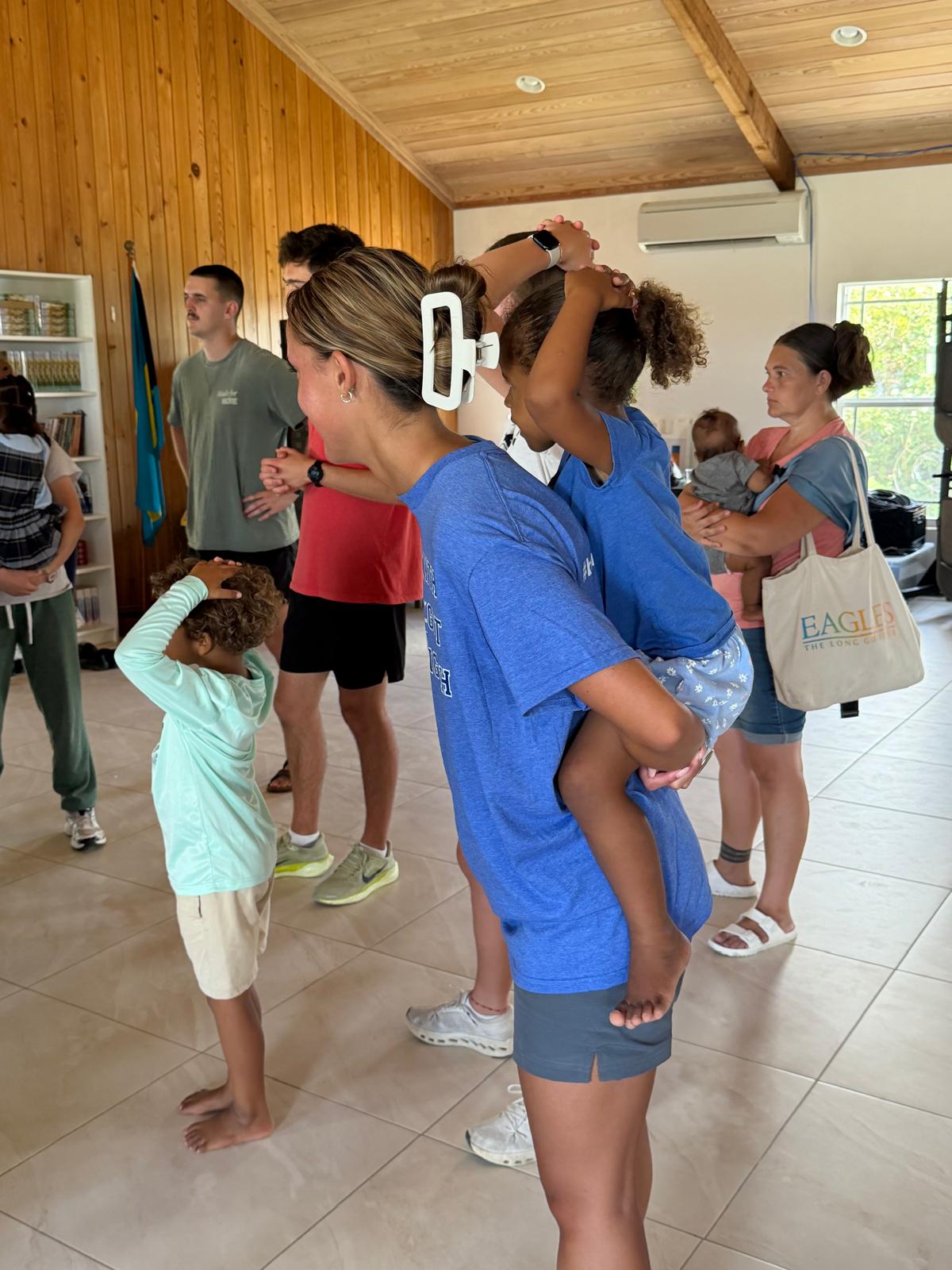 A Lutheran Church of Hope Ames volunteer gives a young girl a piggyback ride at an Abaco church, highlighting the impact of relational ministry and quality time.
