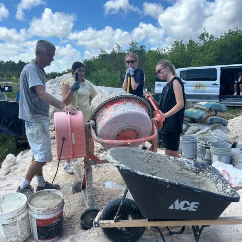 Volunteers utilize a portable mixer to prepare cement for sustainable farm infrastructure development on an Abaco restoration project with Many Hands.