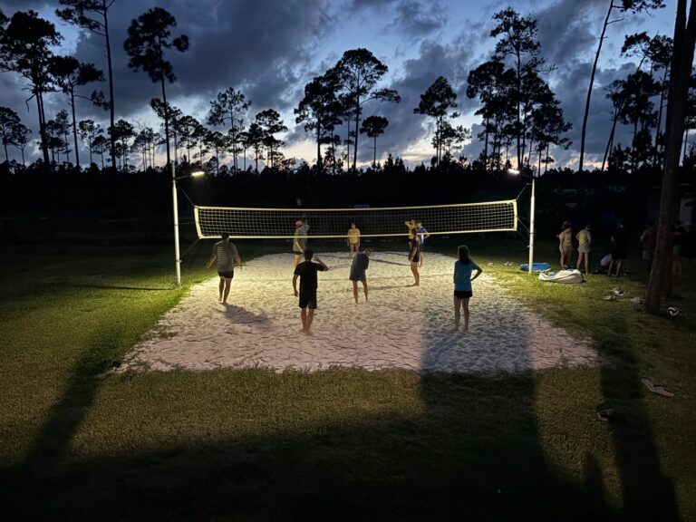 The Many Hands Kairos impact team plays an evening game of sand volleyball during a fellowship event at a local farm, celebrating a week of life transformation and community bonding in Abaco.