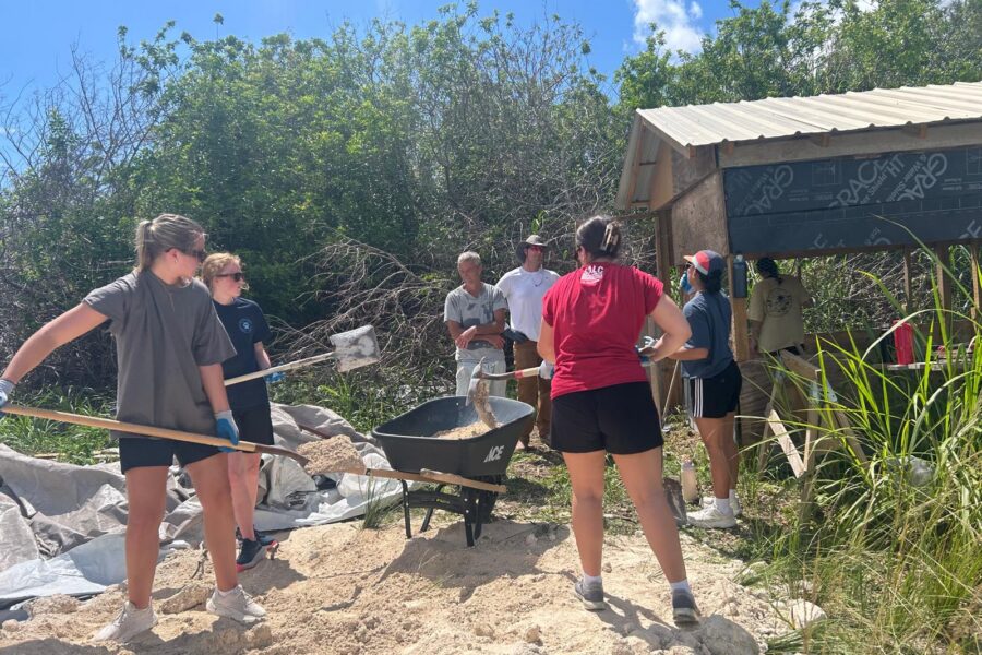 Many Hands team members shovel sand and gravel to mix concrete, dedicating their labor to help local entrepreneurs rebuild their livelihoods after the hurricanes.