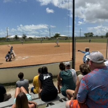 Short-term team volunteers sit in the bleachers to watch and cheer for native Bahamian players, building relational connections through local sports.