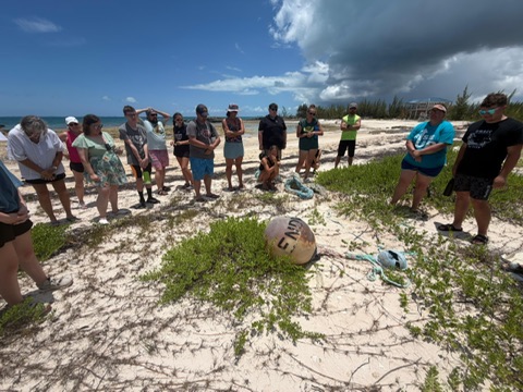 Celebrate Church team members form a large circle on the beach to pray over a potential permanent ministry site for Many Hands' community programs in Abaco.