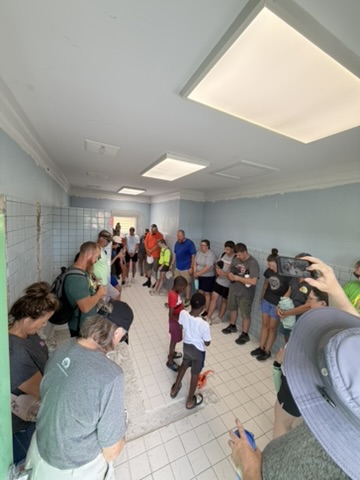 The complete impact team gathers with local students in a circle to pray over a school facility demolition and restoration project at CAPS.