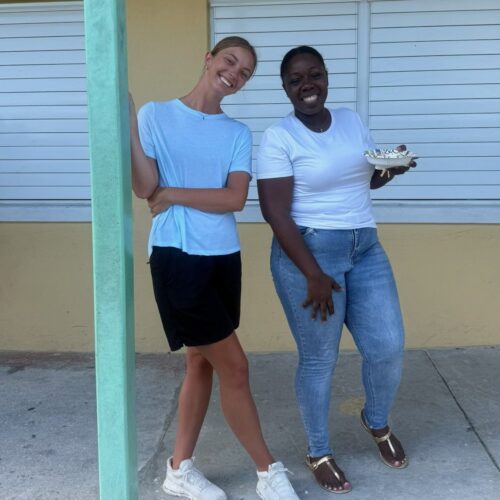 A Celebrate Church team member smiles alongside Many Hands staff member Celekah Mills outside a school building, embodying the collaborative heart of an Abaco impact trip.