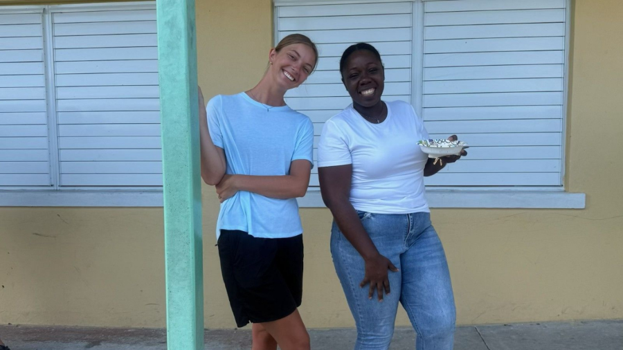 A Celebrate Church team member smiles alongside Many Hands staff member Celekah Mills outside a school building, embodying the collaborative heart of an Abaco impact trip.