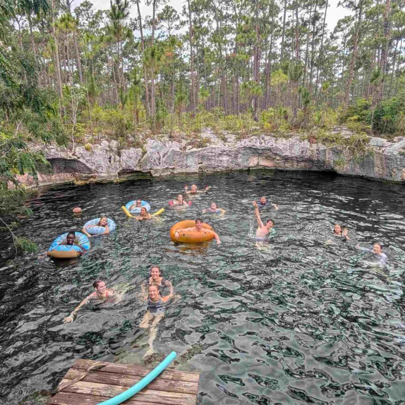 Volunteers from the Des Moines Christian School impact team float on inner tubes and swim together in an Abaco blue hole during a cultural immersion day with Many Hands.