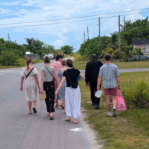 Many Hands volunteers walk down a local road in Abaco to hand-deliver food distribution bags directly to the homes of families facing economic hardships.