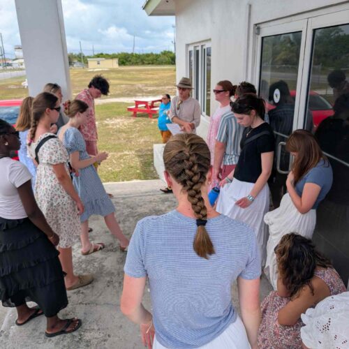 Members of the Des Moines Christian School impact team bow their heads in a prayer circle before distributing essential food to local families in Spring City, Abaco.