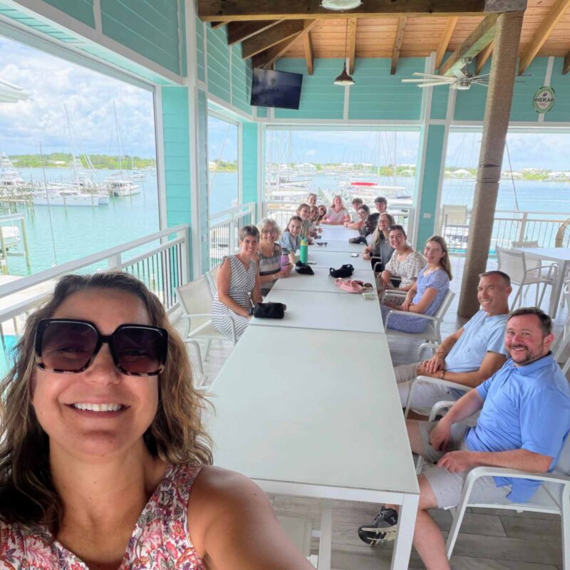 The Des Moines Christian School impact team gathers around a long table for a fellowship lunch at the Jib Room restaurant, overlooking a marina during their Many Hands trip to Abaco.