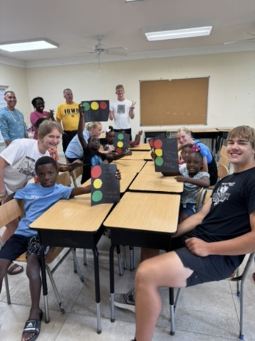 Volunteers from the Immanuel CRC youth group pose with local children displaying completed traffic light paper crafts during a reading picnic.