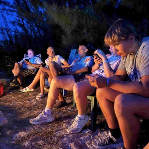 Volunteers and leaders gather around a evening campfire at Camp Abaco to share impact stories, reflect on local hospitality, and build deeper team fellowship.