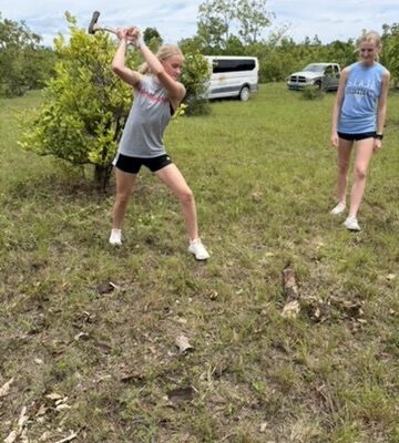 immanuel-youth-farm-1 An Immanuel CRC youth volunteer swings an axe to clear brush around fruit trees, supporting agricultural development and farm optimization during a Many Hands trip in Abaco.