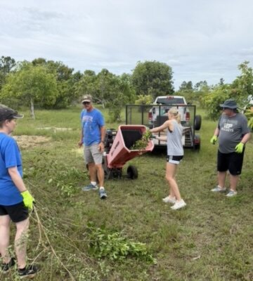 immanuel-youth-farm-cleanup Youth impact team members and local site leaders process cut branches through a wood chipper to clean up a local Abaco farm orchard.