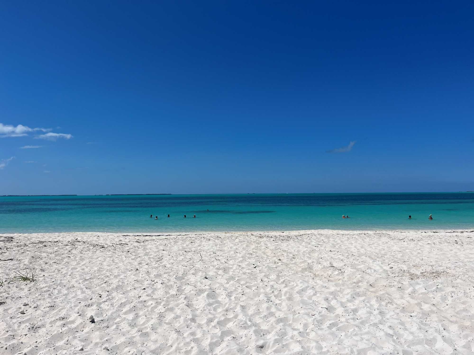 A serene view of white sand and crystal-clear turquoise waters at Treasure Cay, providing a space of peaceful rest and renewal for short-term volunteers.