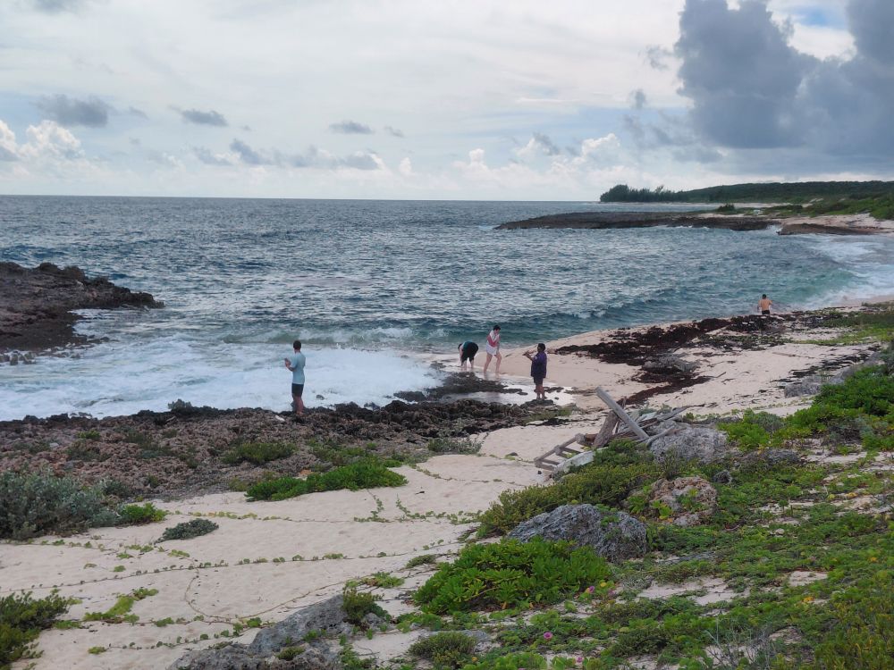 Impact team members gather along the rocky shoreline and sandy beach in Abaco, experiencing rest and reflection in God's creation.